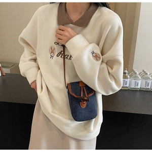 Close-up of mini denim crossbody bag with brown leather flap and drawstring detail