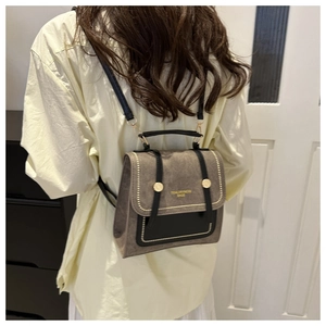 Close-up of vintage dark grey suede backpack with leather straps and gold metal details