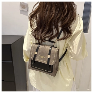 Rear view of a model wearing a taupe suede crossbody square bag in a modern room