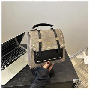 Detail of gray-brown textured handbag with black leather trim and gold metal buckles