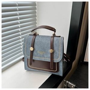 Detail view of vintage blue matte handbag featuring gold rivets and brown leather handles