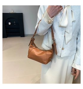 Detail einer braunen Leder-Schultertasche mit verstellbarem Riemen und Reißverschluss-Dekor