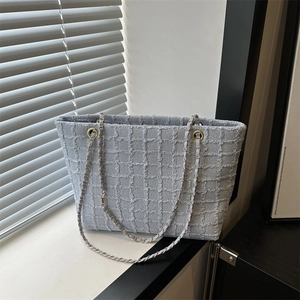 Light blue woven chain tote bag with gold hardware and elegant textured finish