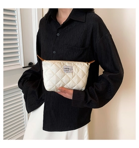 Gros plan sur la pochette matelassée blanche avec étiquette mode et zip doré
