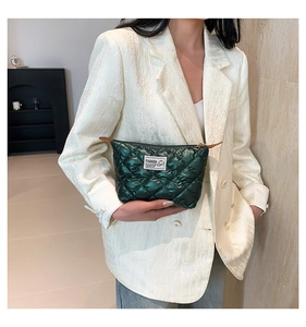 Gros plan sur la pochette en nylon matelassé vert avec étiquette mode et tirette en cuir