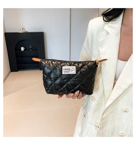 Vue détaillée de la pochette matelassée noire en nylon avec étiquette et détails en cuir brun