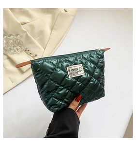 Détail de la pochette matelassée vert foncé avec finition brillante et étiquette textile