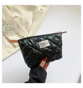 Détail de la pochette matelassée noire avec broderie losange et étiquette tendance