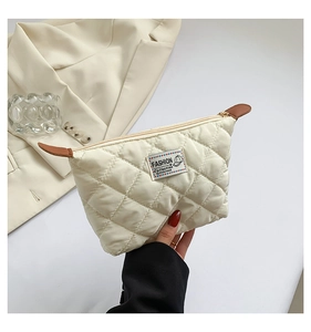 Vue détaillée de la pochette matelassée crème avec couture en losange et zip doré brillant