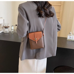 Brown patchwork crossbody phone bag shown on a model in a minimalist cafe setting
