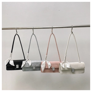 Detail of four stylish flap bags in black, grey, pink and beige with silk scarf accents