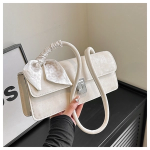 Detailed view of cream crossbody bag with rhinestone buckle and silk scarf handle