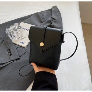 Detail of black leather mini crossbody phone bag with gold clasp and textured finish