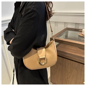 Detail of light brown crescent shoulder bag with golden D-ring buckle on a female model