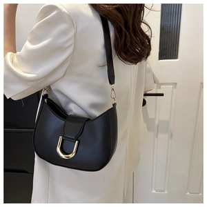 Detail of black leather hobo bag with a prominent U-shaped gold metallic buckle