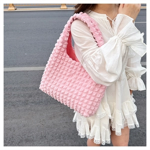Detail of pink popcorn textured shoulder bag showing elastic bubble fabric and soft pleats