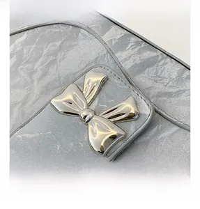 Detail of silver metallic bow buckle and marble texture leather on underarm bag