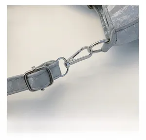 Close-up of silver metal lobster clasp and buckle on a silver textured crossbody bag