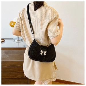 Detail of black hobo bag with jacquard texture and silver bow buckle on model