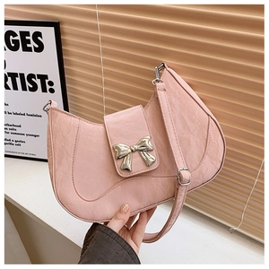Detail of light pink crescent bag featuring pleated texture and golden bow buckle clasp