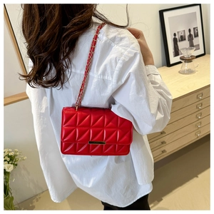Vista laterale di una borsa a tracolla rossa trapuntata con catena dorata su una modella