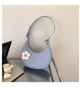 Borsa a spalla a mezza luna azzurra con ciondolo a fiore bianco e logo impresso