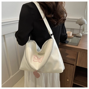 Macro detail of large white PU leather tote with pink butterfly embroidery and heart charm