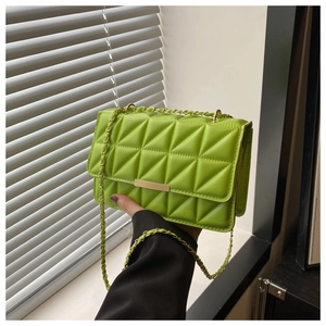 Dettaglio borsa trapuntata verde neon con tracolla a catena dorata e fibbia metallica