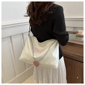 Detailed view of pearl white PU leather bag with pink butterfly embroidery and heart charm