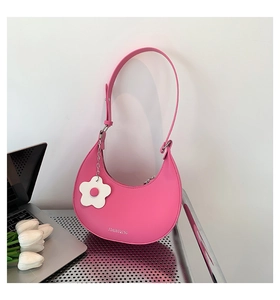 Dettaglio della borsa a tracolla rosa a mezzaluna con ciondolo a fiore bianco elegante
