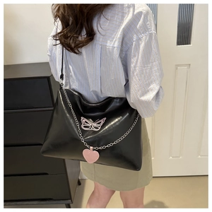 Detail of black tote bag with pink butterfly embroidery and silver heart chain