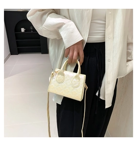 Detail of cream mini square bag featuring quilted diamond pattern and a top handle