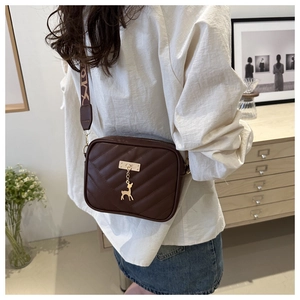 Détail du sac bandoulière marron chocolat avec matelassage et pendentif cerf doré