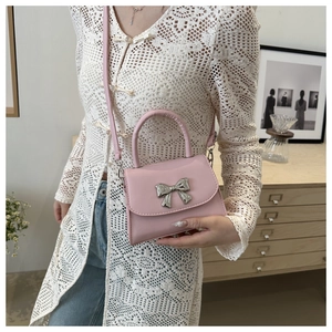 Close-up of pink leather crossbody bag with metallic silver bow detail and top handle