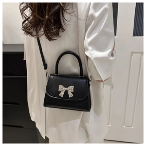 Detailed back view of a woman wearing the black bow-knot crossbody bag in a modern room