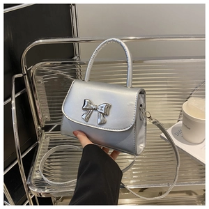 Detailed view of silver metallic handbag with bow accent and detachable shoulder strap