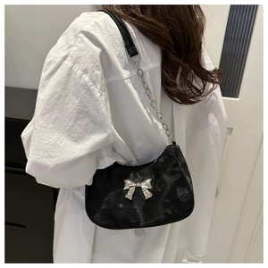 Close-up of black fuzzy underarm bag featuring a metallic silver bow and chain strap