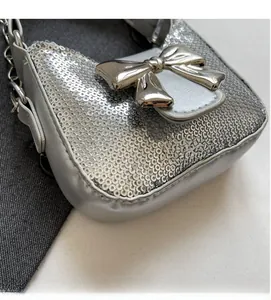 Vue détaillée d'un mini sac argenté à paillettes avec un grand fermoir nœud en métal