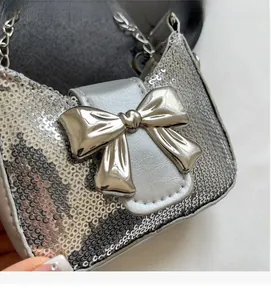 Détail du mini sac à paillettes argentées avec un grand nœud métallique et chaîne