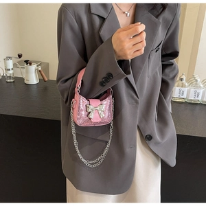 Vue détaillée du sac rose à paillettes avec boucle en nœud argenté et bandoulière chaîne