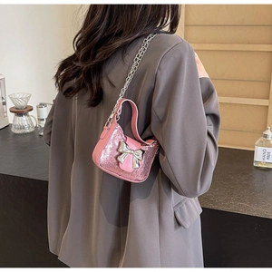 Mini sac à paillettes roses avec nœud argenté porté sur un mannequin en tailleur