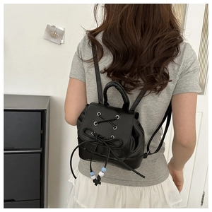 Detail of black leather mini backpack featuring ballet style ribbons and beaded drawstring