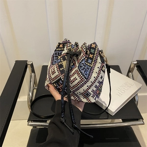 Ethnic knit drawstring bucket bag with colorful geometric patterns and black leather strap
