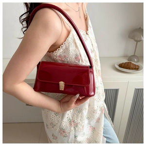 Detail of burgundy glossy underarm bag with golden square buckle and minimalist design