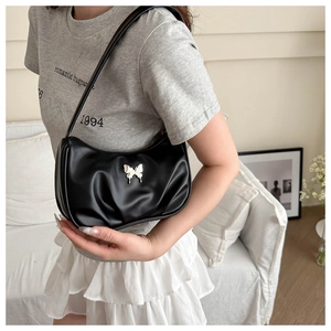 Détail du sac sous le bras noir plissé avec boucle papillon argentée et bandoulière en cuir