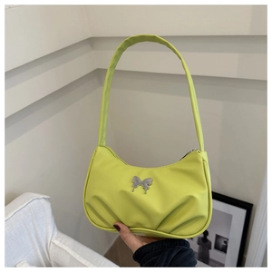 Détail d'un sac sous les bras en similicuir vert néon avec boucle papillon argentée