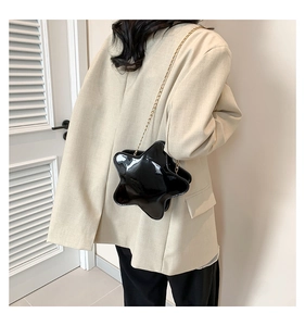 Star-shaped black faux leather crossbody bag with gold chain strap on model