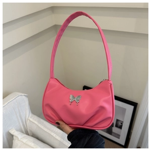 Gros plan d'un sac sous le bras en similicuir rose avec ornement papillon et plis élégants