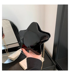 Détail macro du sac noir en cuir verni en forme d'étoile avec bandoulière chaîne dorée