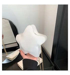 Gros plan d'un sac blanc en forme d'étoile en cuir verni avec une chaîne en métal doré